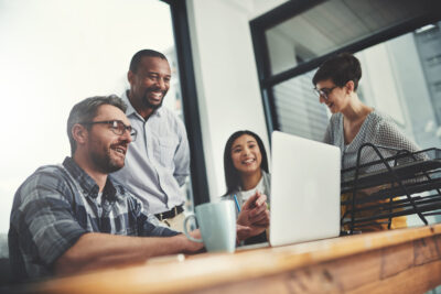 A group of workers gathered around a laptop