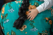 A young child's arm draped over their parent's back.