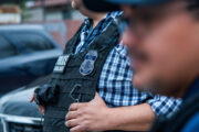 The torso of an ICE officer with a black vest on