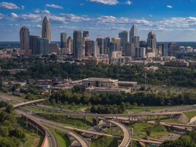 Aerial view of Charlotte, North Carolina, featuring the downtown skyline, office towers, highways, and surrounding neighborhoods in Mecklenburg County.