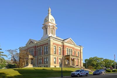 Historic courthouse building in Wabash County, Indiana, featuring a clock tower, red brick and limestone architecture, and a landscaped lawn under a clear blue sky.